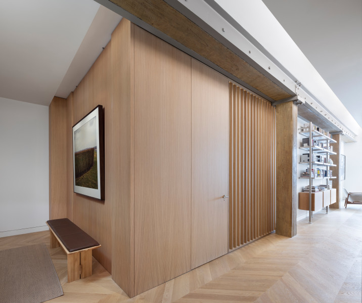 Entrance vestibule, with oak wood wall panel cladding, chevron pattern wood flooring and refinished old wood beams reminiscent of the original wood structure of the building.