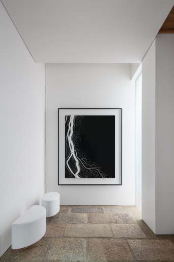 Entrance vestibule view, with one of Hiroshi Sugimoto's photographs surrounded by shikkui plaster walls and recycled stone paver floor.