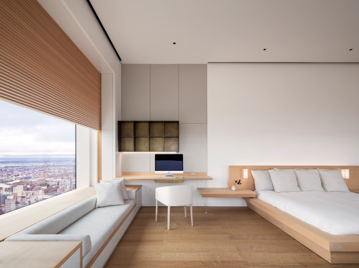 View of master bedroom, with hand-carved chestnut wood flooring, built-in window seating, custom cedar built-in desk, and bed., custom patina bronze bookshelf, shikkui plaster walls, and operable wooden screen in front of large window.