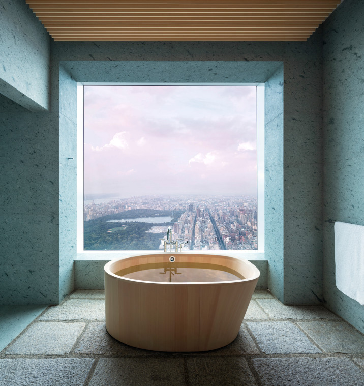 Bathroom view, with traditional Japanese wooden bath tub in foreground, recycled stone paver floor, green tuff stone clad walls, with large, square window overlooking Central Park.
