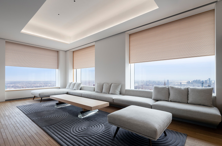 View of family room, with custom upholstery seating, shikkui plaster walls, custom carpet, and operable wooden screens in front of windows overlooking Manhattan and Queens.