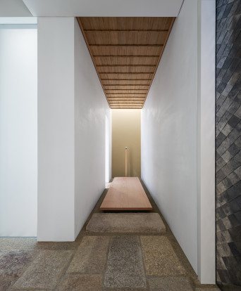 Entrance vestibule and corridor view, with a modern interpretation of a traditional Japanese wooden entrance threshold (shikidai) and custom wood ceiling.