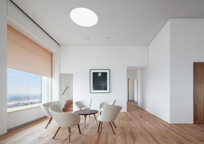 View of living room with custom-made furniture, Yakusugi cedar flooring, shikkui plaster walls and operable wooden screen in front of window.