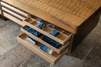 Detail view of 45R's new clothing store in Soho, New York, showing a hand-carved chestnut display table with open merchandise drawers.