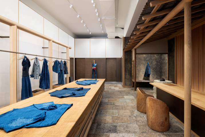 Overall view of 45R's new clothing store in Soho, New York, with clothing display rackets, display tables and bronze-clad customer service counter.